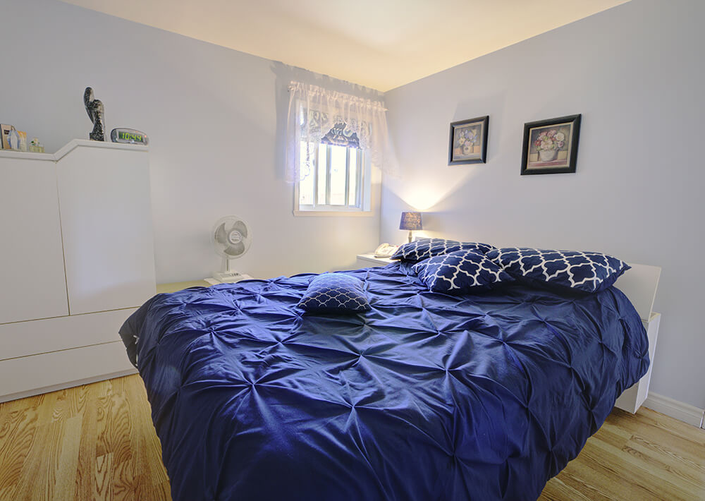 Chambre avec lit bleu d'un logement 4 1/2 des résidences Melrose
